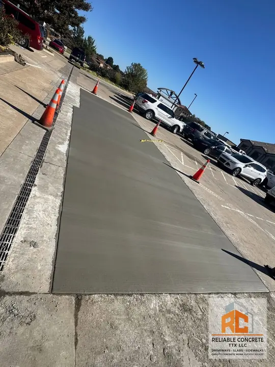 Long strip of fresh concrete poured beside a parking area
