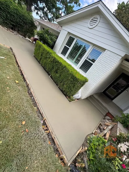 Finished side walkway along a white house with hedges